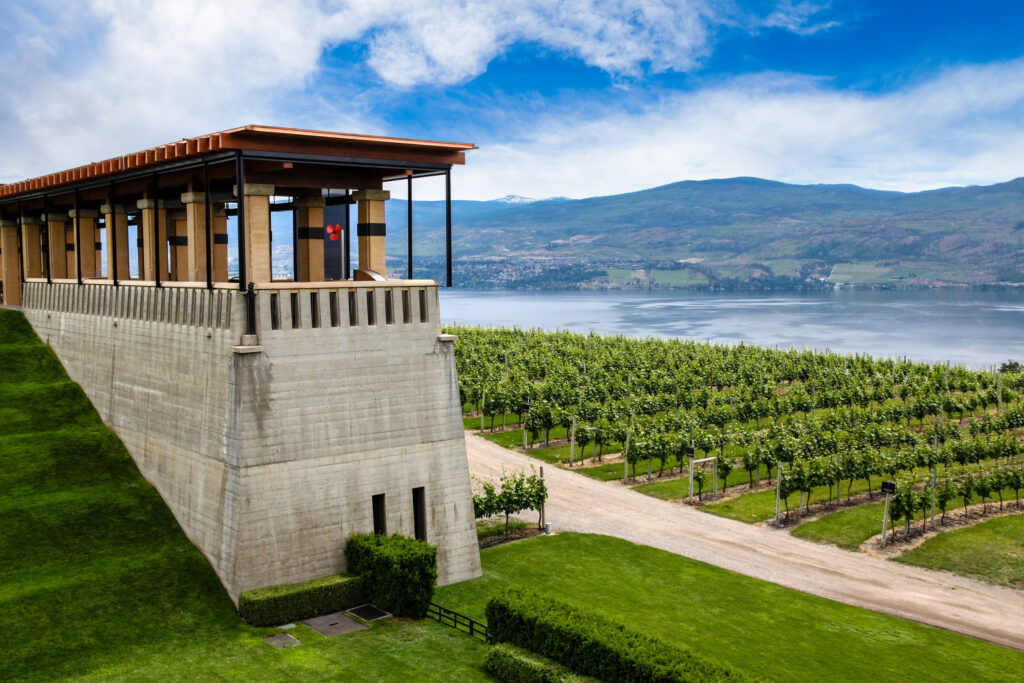 Winery building with a stone terrace above vineyards and a lake in the Okanagan