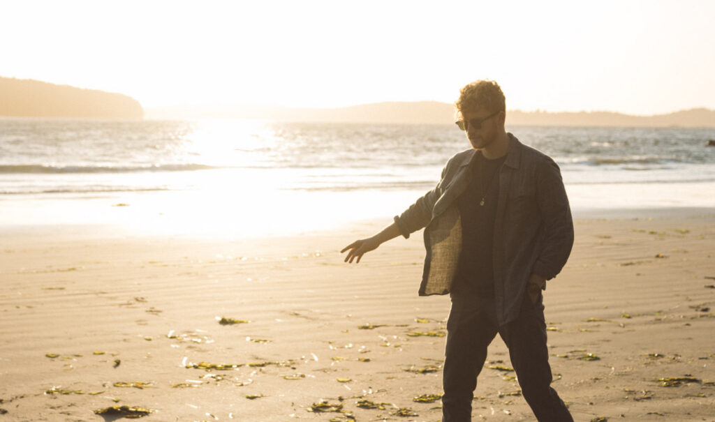 Nick Hemingway walking along a sunlit beach at sunset