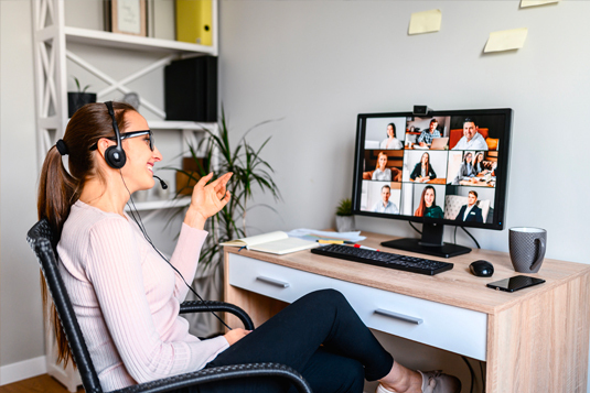 Woman wearing a headset leading a video meeting on a desktop monitor