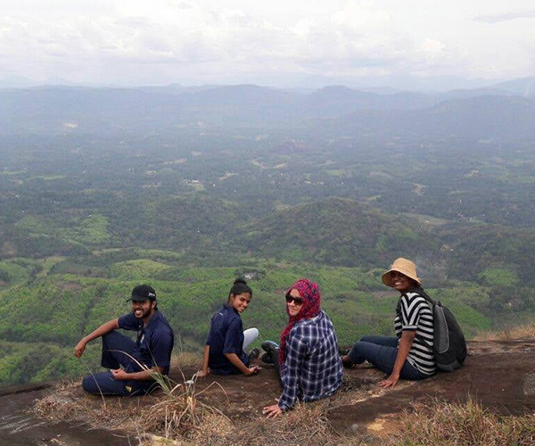 Shana and three companions sitting on a hilltop overlooking green valleys