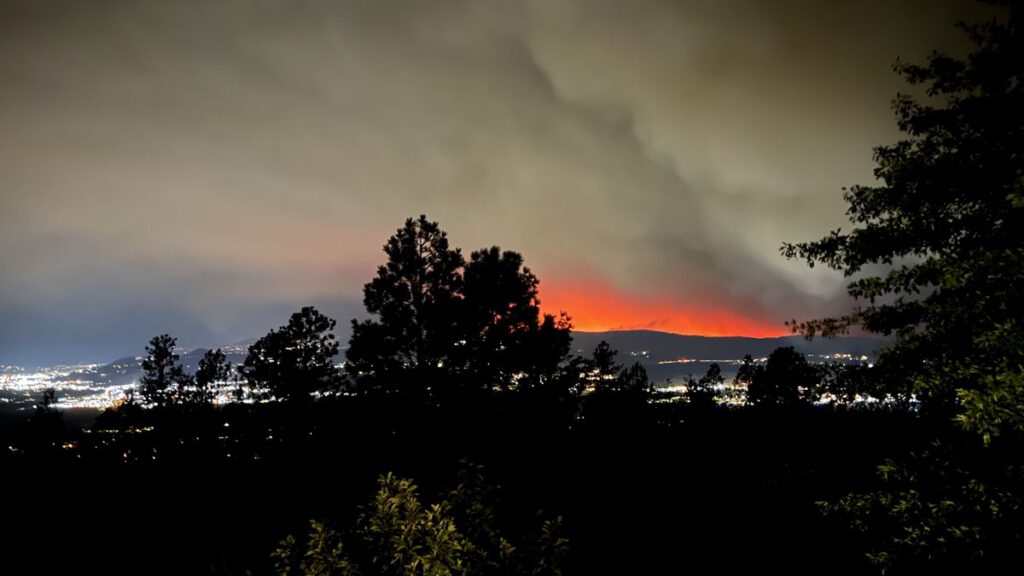 Orange wildfire glow on a hillside above Kelowna at night