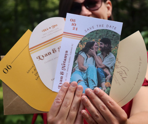 Jocelyn holding wedding save-the-date cards and envelopes in a printed invitation suite