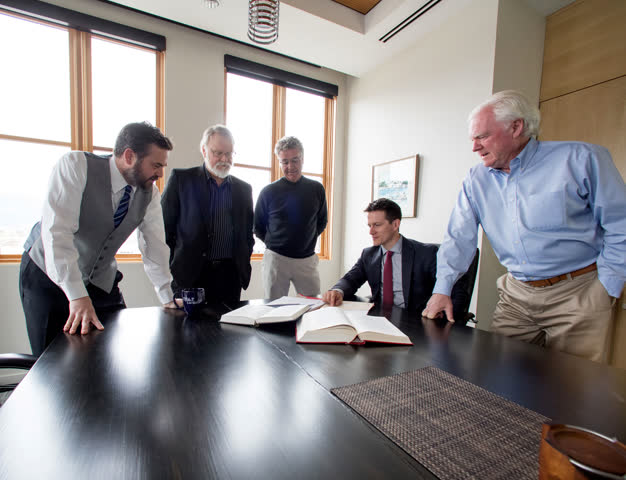 Lawyers from FH&P gathered around a boardroom table reviewing an open legal book