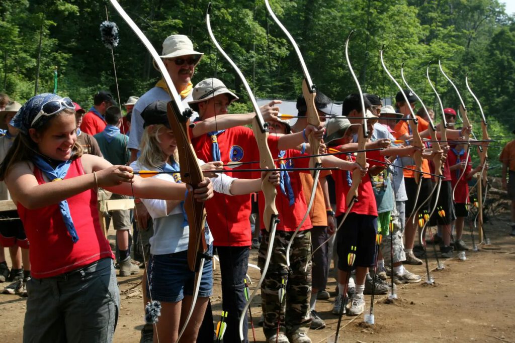 Scouts Canada youth in red shirts lined up practising archery