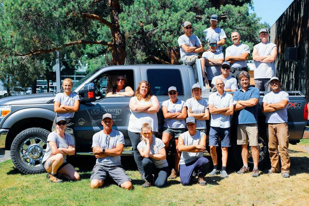 Synergy Landscape Design crew posed around a work truck on a lawn