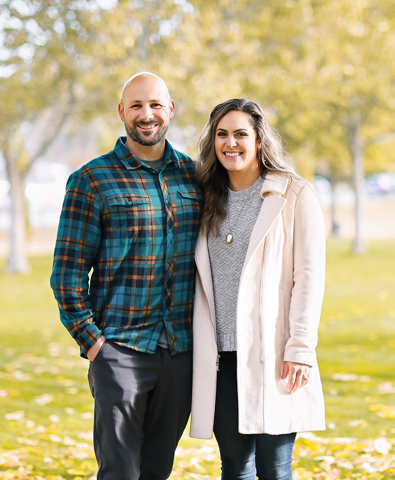 A smiling couple stands arm in arm in a sunny park for GreenTree Community Inclusion Programs