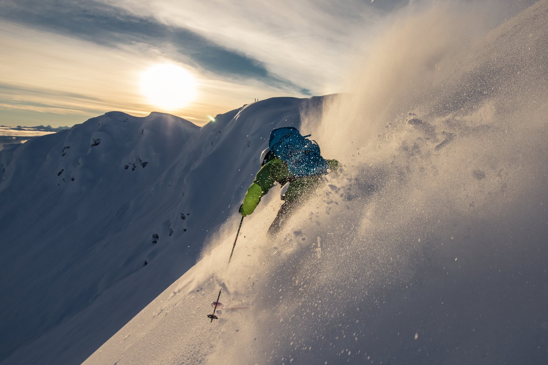 A skier dropping into steep powder at sunrise