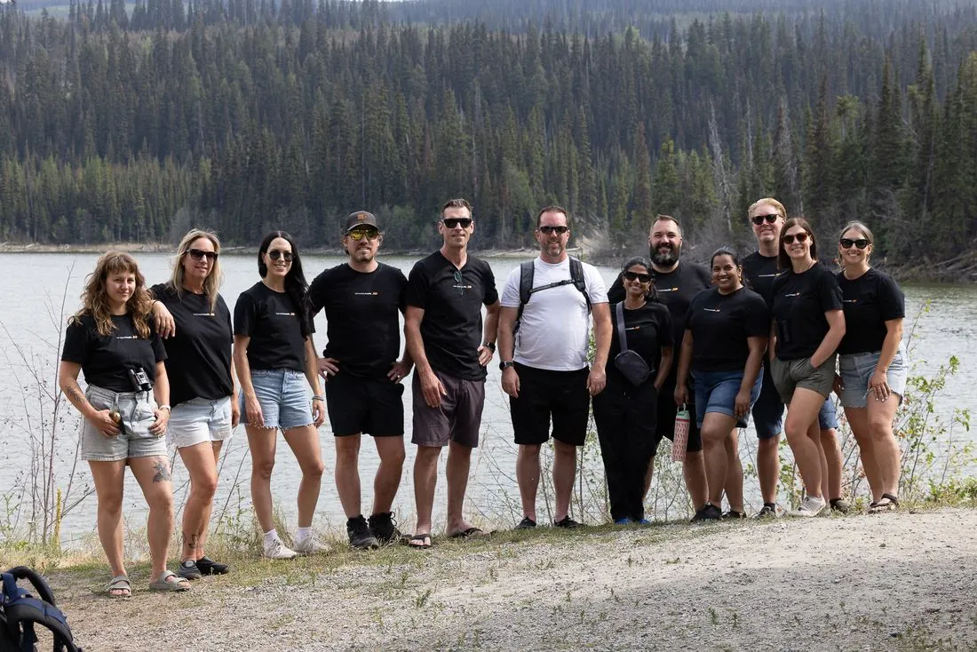 The whole Twin Creek Media team lined up by a lake